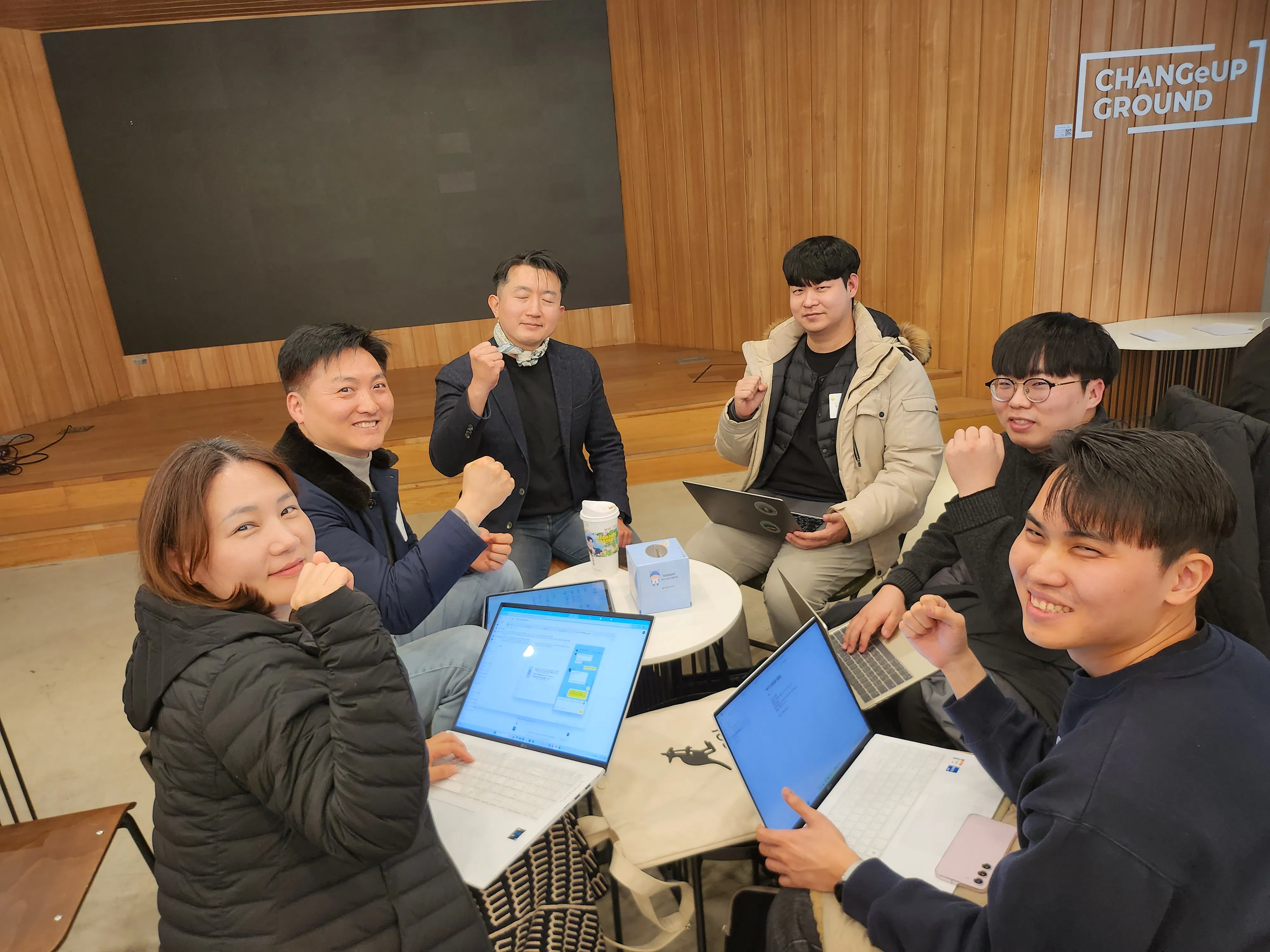 노트북을 들고 테이블 주위에 앉아 있는 한 무리의 사람들