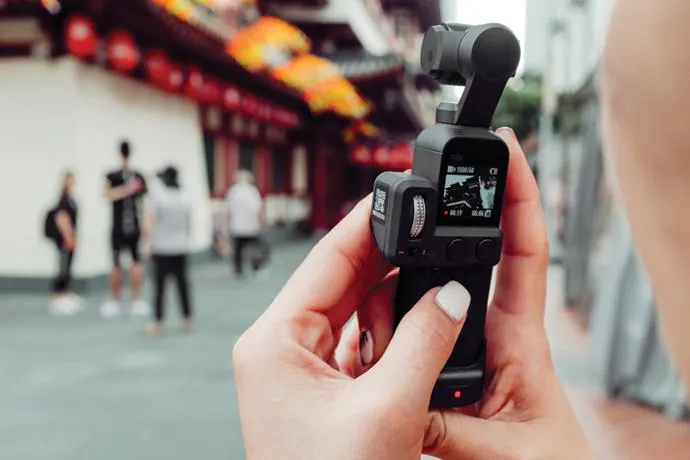 건물 앞에서 작은 카메라를 들고 있는 사람