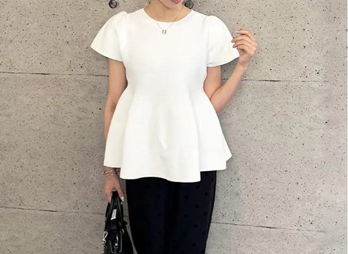 흰색 peplum 상단과 검은 색 바지를 입은 여자