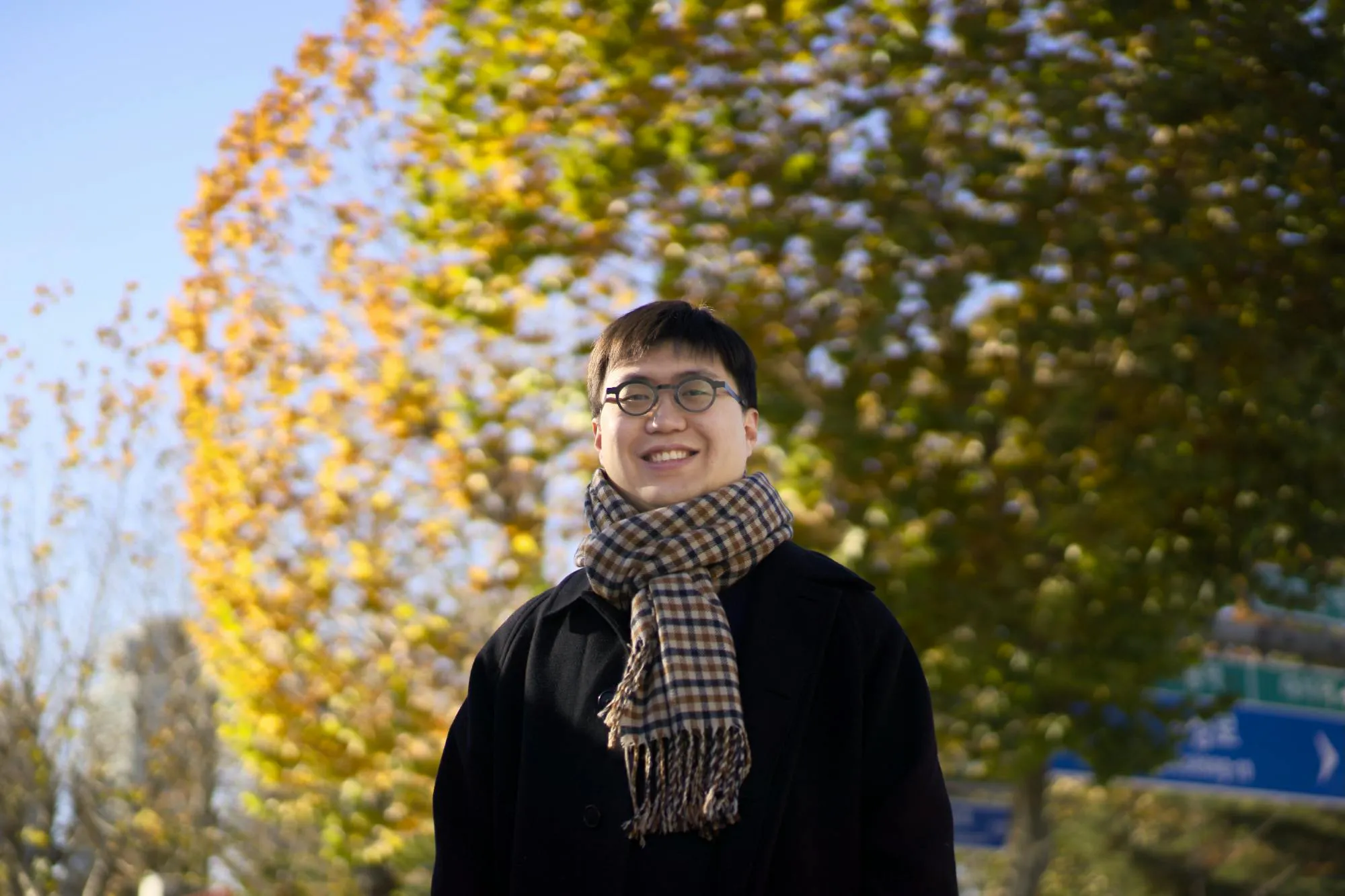 안경을 쓰고 나무 앞에서 스카프를 입은 남자