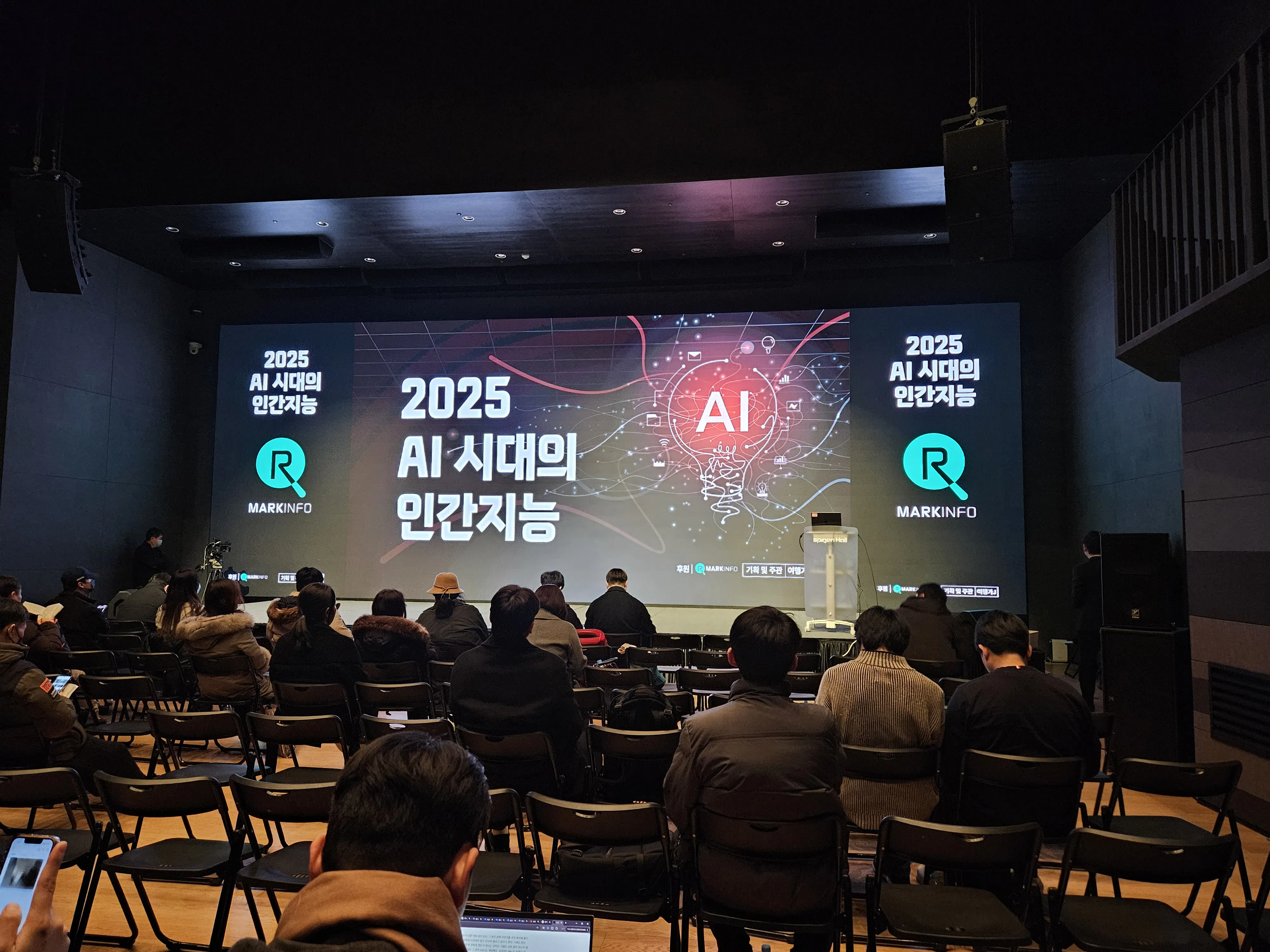 큰 스크린 앞에 앉아 있는 한 무리의 사람들