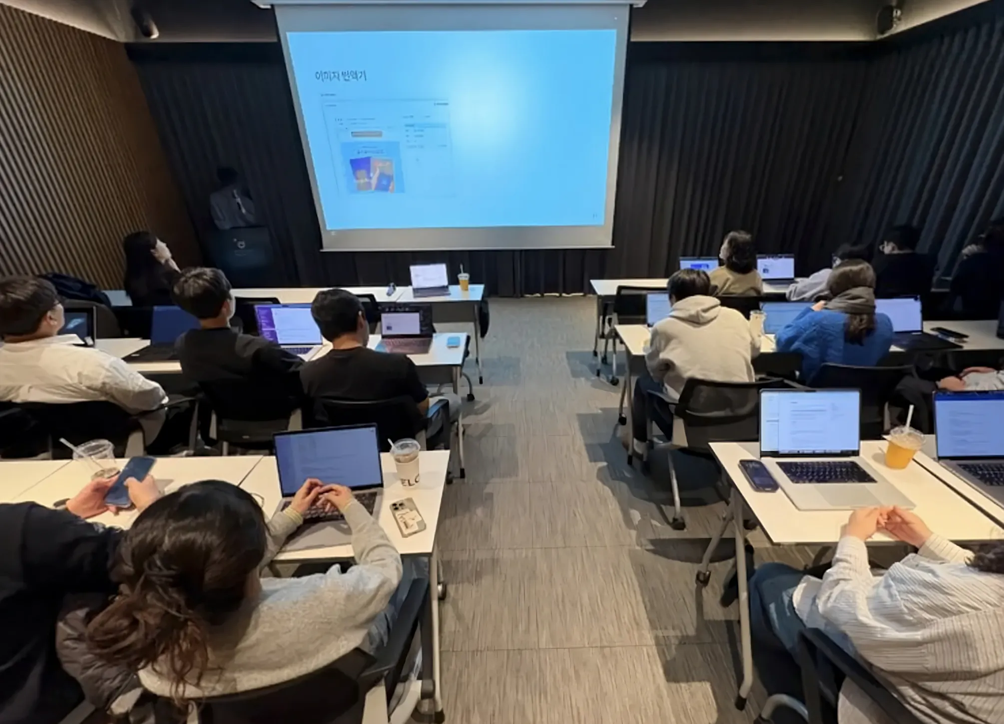 노트북을 앞에 두고 책상에 앉아 있는 한 무리의 사람들