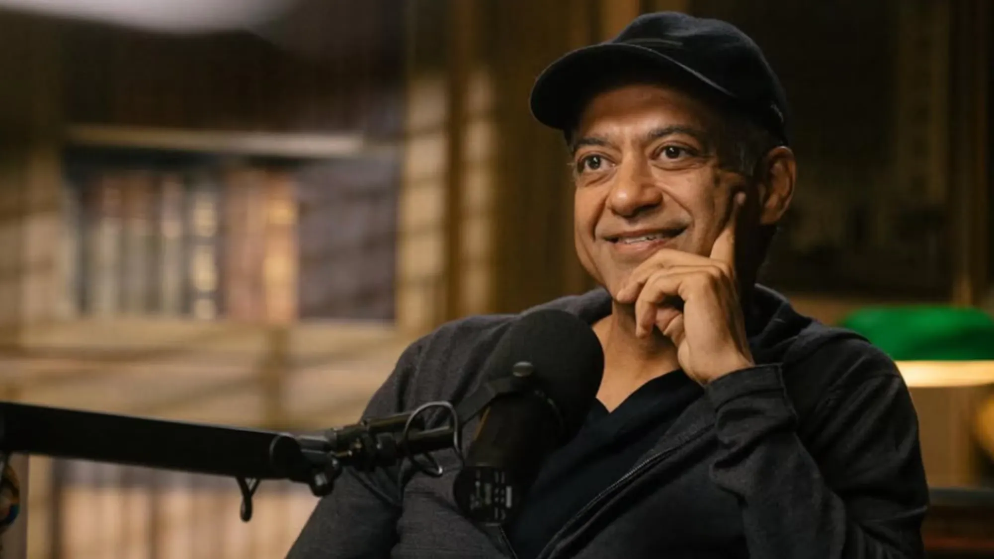 검은 모자를 쓴 남자가 마이크 앞에 앉아 있다