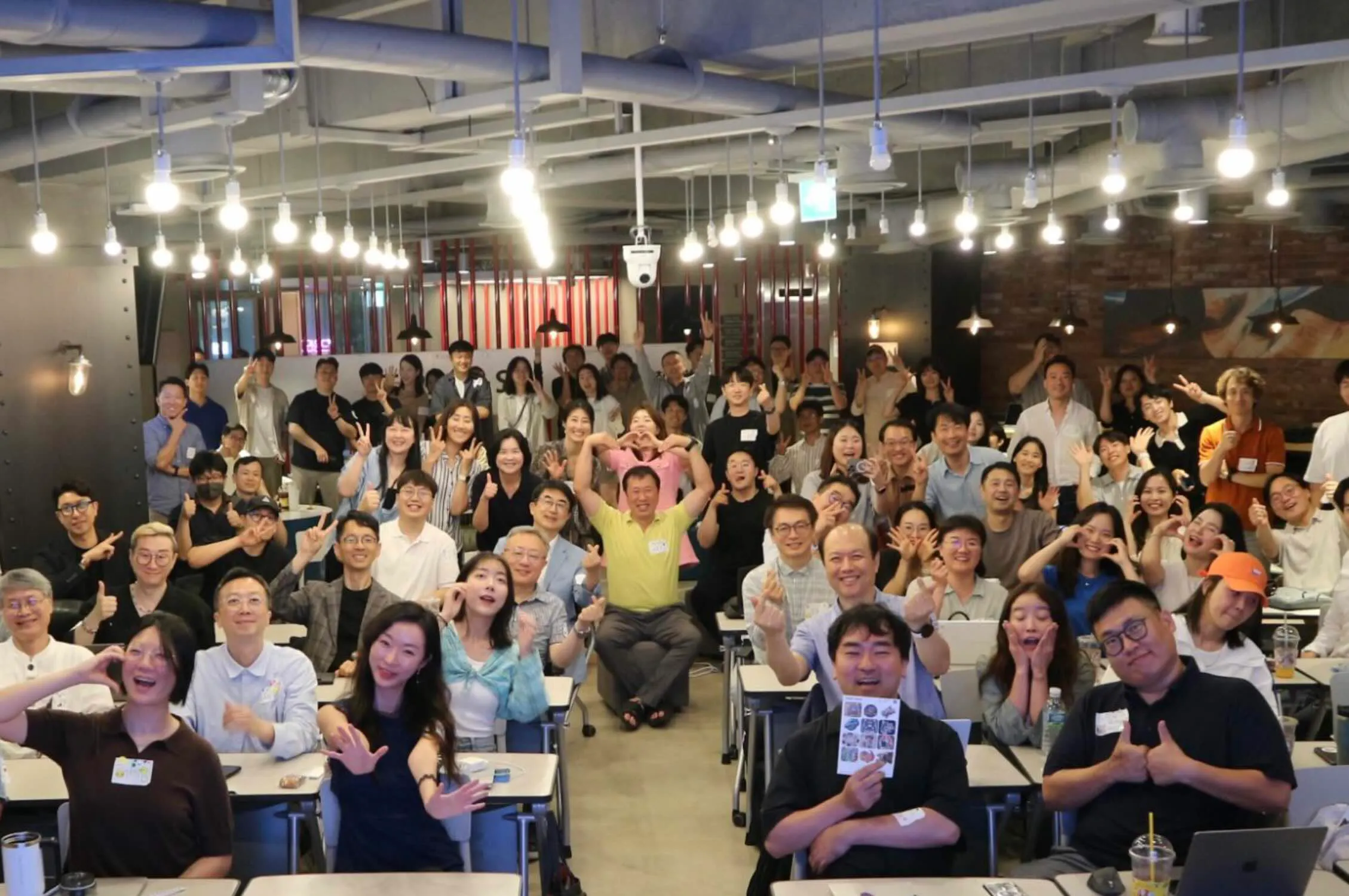 한 무리의 사람들이 방에서 카메라를 향해 포즈를 취하고 있다