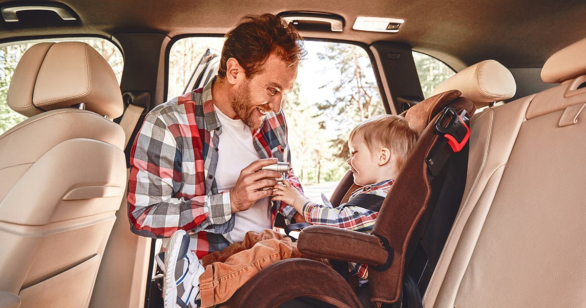 man putting baby in  a car seat