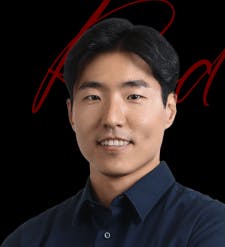 파란 셔츠를 입은 남자가 검은 배경 앞에 서 있다