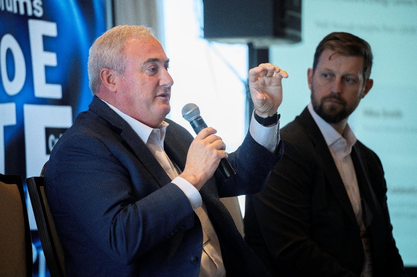 A person holding a microphone and another person in a suit

AI-generated content may be incorrect.