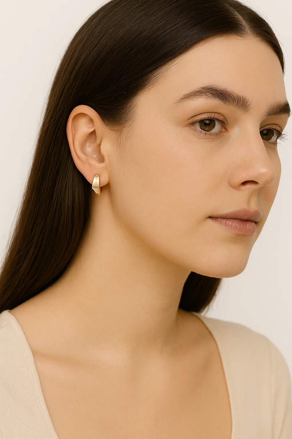 모델은 금 스터드 귀걸이 한 쌍을 착용하고 있습니다.