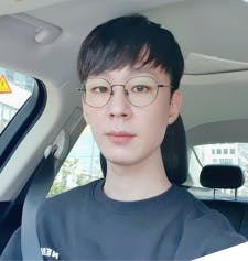 안경을 쓴 젊은 남자가 차 뒷좌석에 앉아 있다