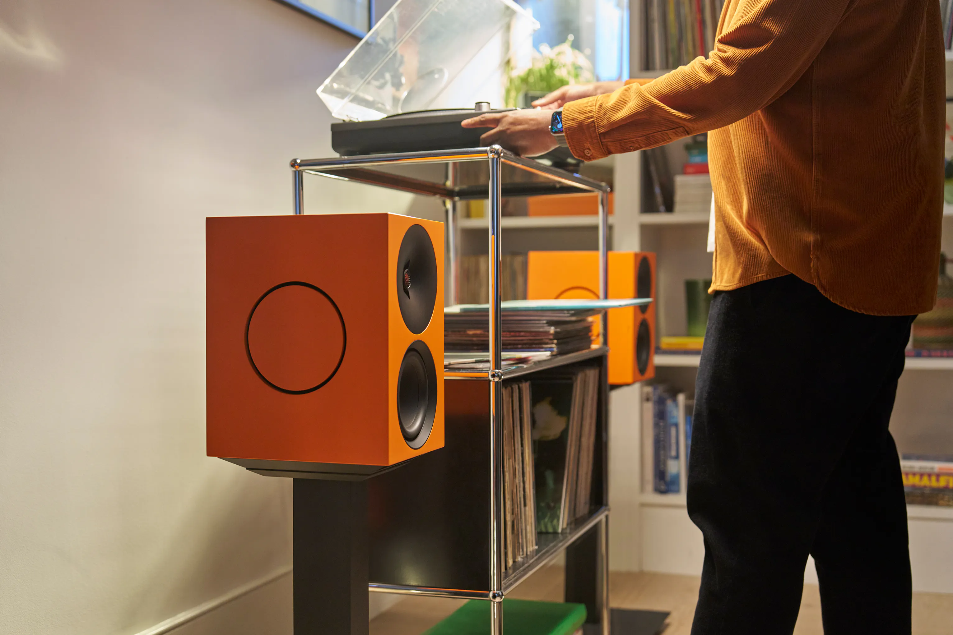 Reaching for the turntable on a glass hi-fi rack, L/R X active speakers either side.