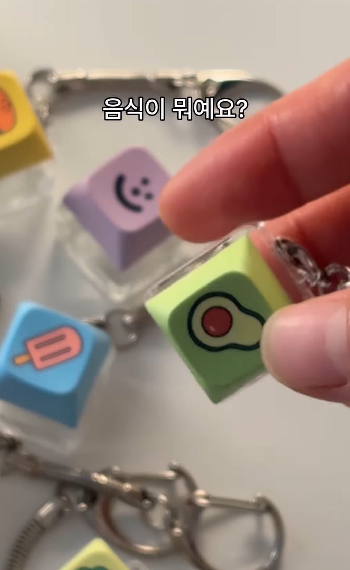 사람이 한국 음식이 다른 키 체인을 들고 있습니다.