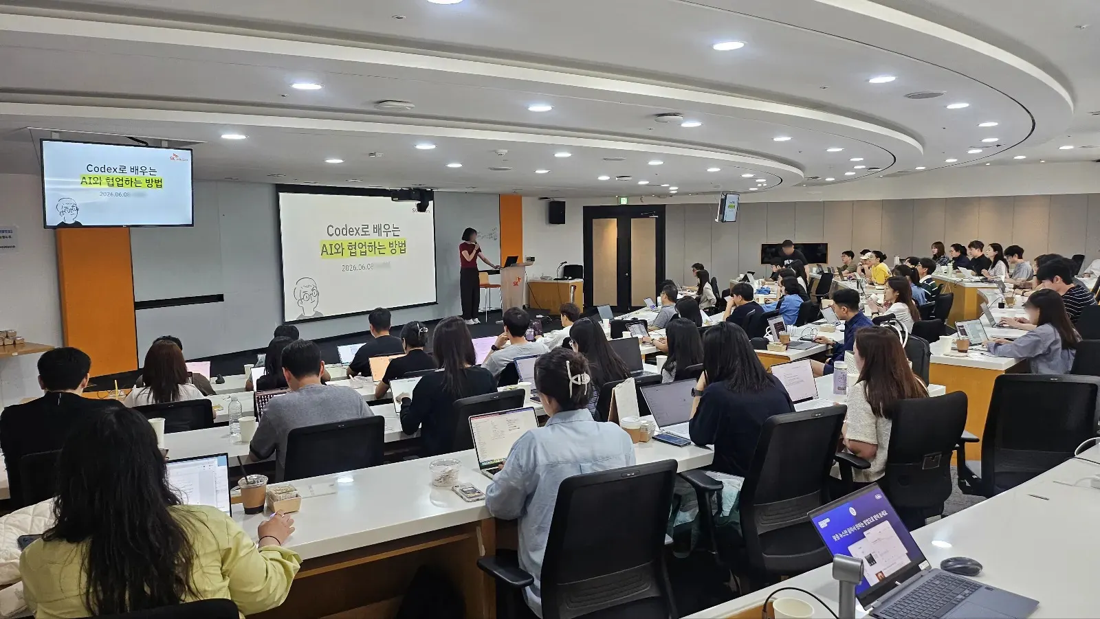 지피터스 기업교육 현장. Codex로 배우는 AI와 협업하는 방법이라는 강의 화면 앞에서 수강생 수십 명이 노트북으로 실습하고 있다