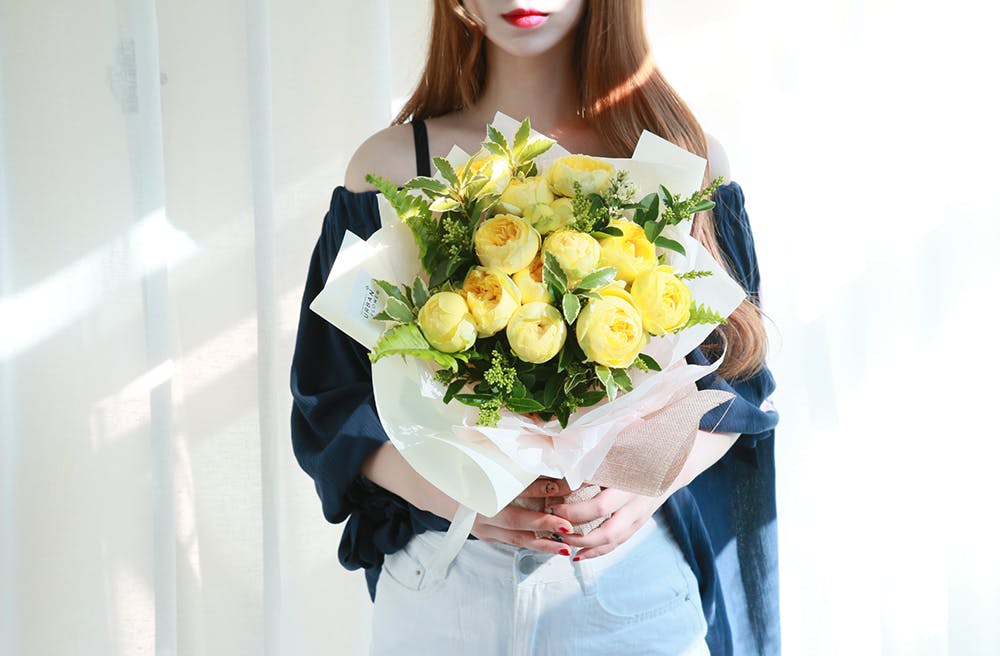 노란 장미 꽃다발을 들고있는 여자