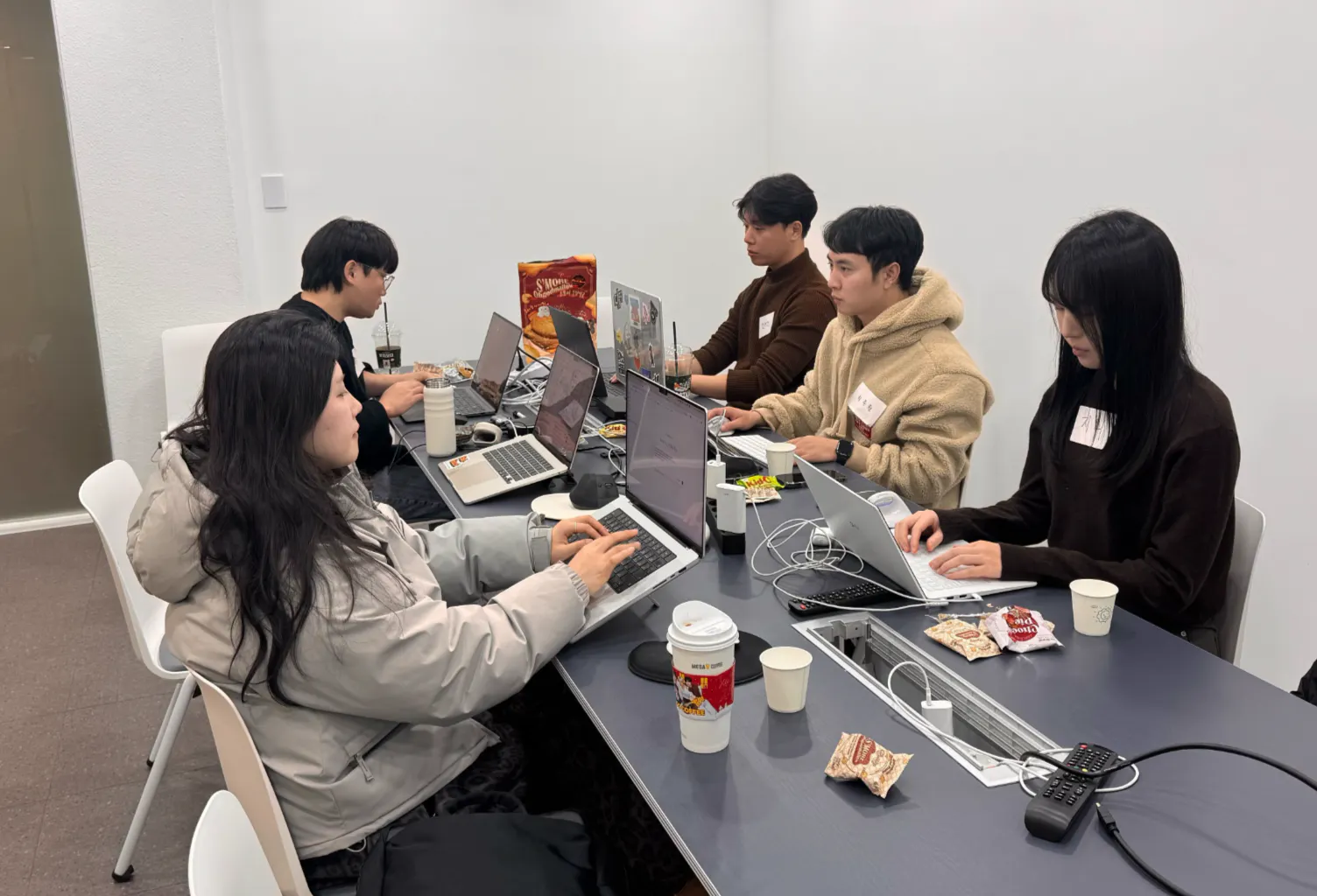 노트북을 들고 테이블 주위에 앉아 있는 한 무리의 사람들