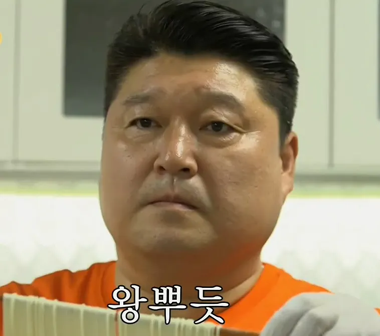 오렌지색 셔츠를 입은 남자가 종이 한 장을 들고 있다