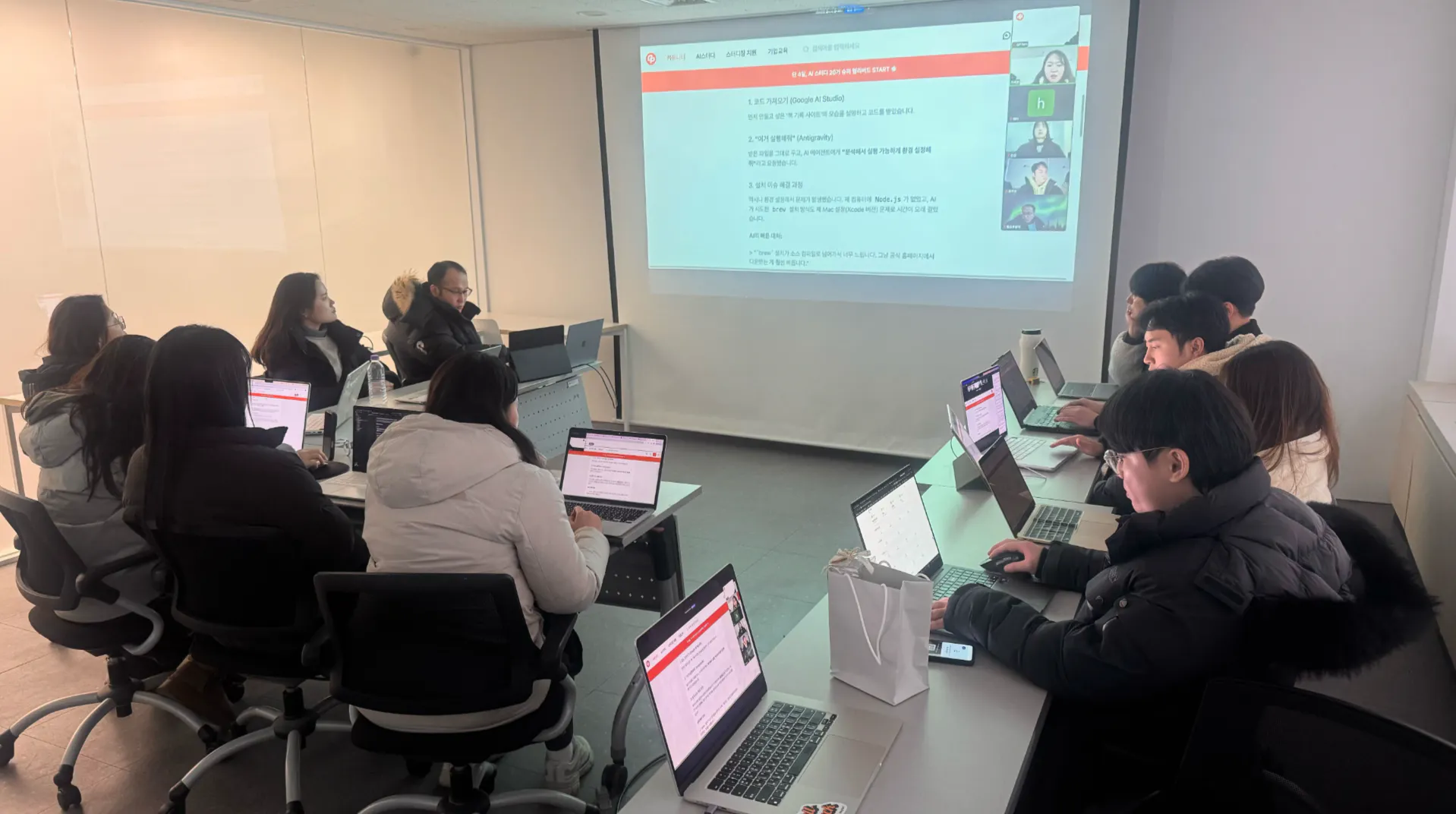 한 무리의 사람들이 테이블에 앉아 노트북을 앞에 두고 있습니다.