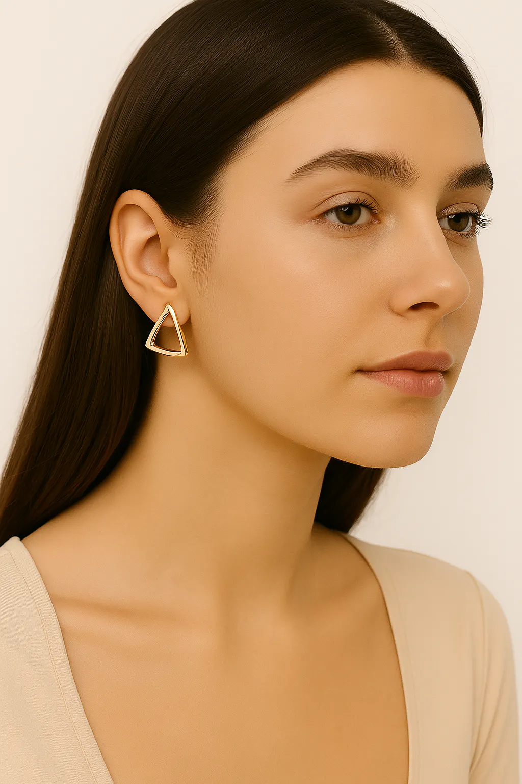 모델은 금 삼각형 귀걸이 한 쌍을 착용하고 있습니다.