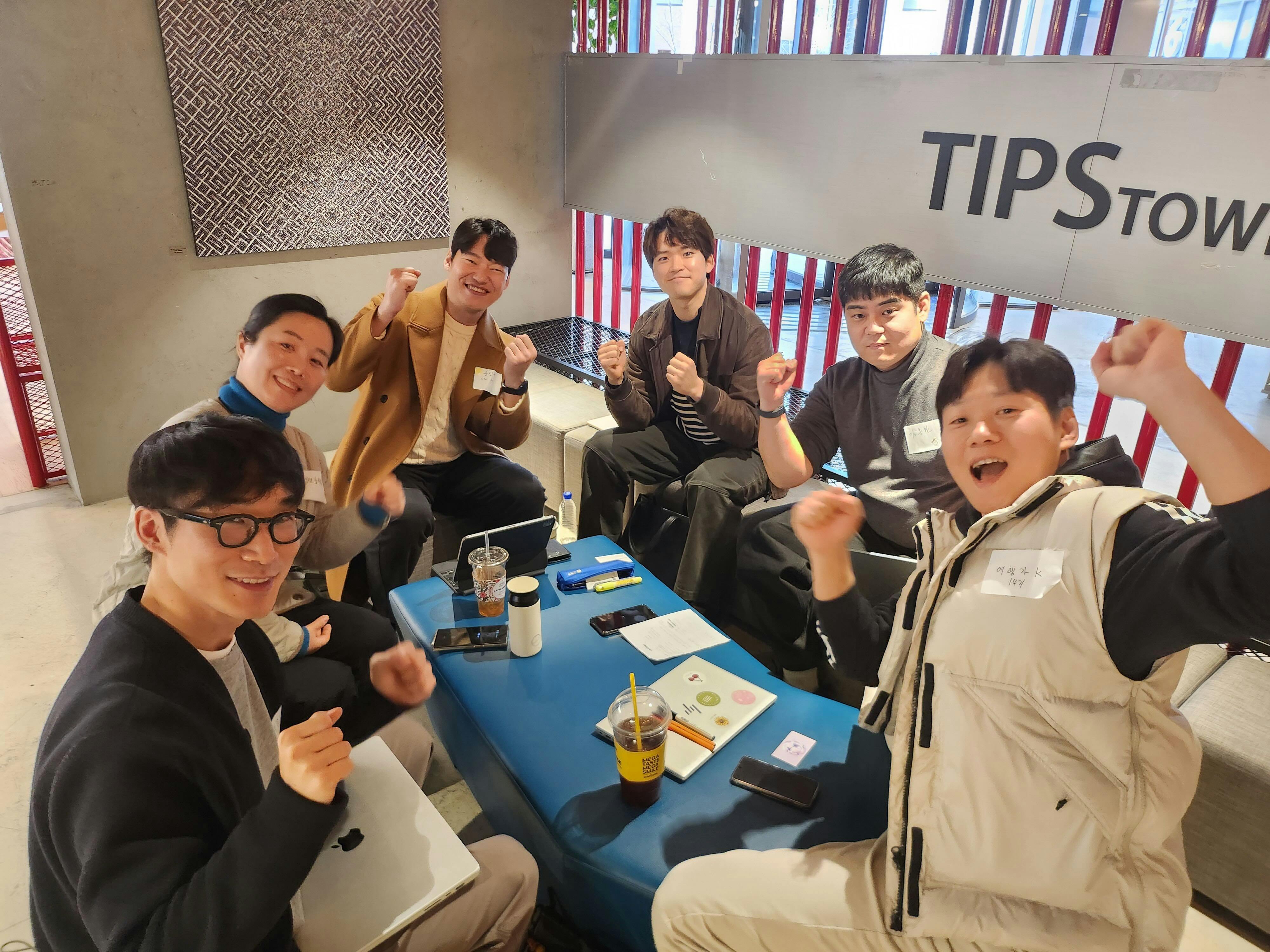 한 무리의 사람들이 커피숍의 테이블 주위에 앉아 있다