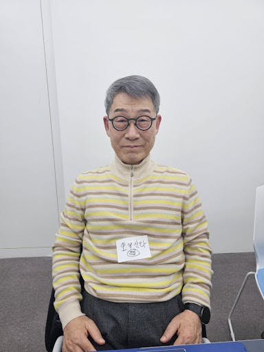 줄무늬 스웨터를 입은 남자가 테이블에 앉아 있다